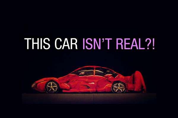 Illusion eines roten Sportwagens, der vollständig aus bemalten menschlichen Körpern geformt ist, mit dem Text „This Car isn’t Real?!“ darüber.
