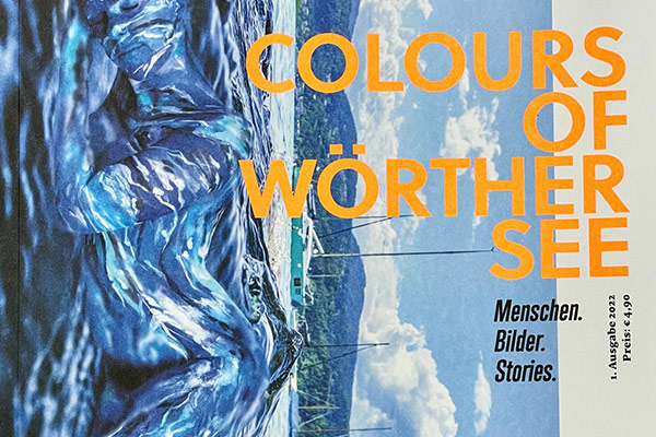 Magazincover „Colours of Wörthersee“ mit einem künstlerisch bemalten Körper im Wasser und dem Titeltext in großen orangefarbenen Buchstaben.