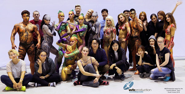 Gruppenfoto des WB Production Teams in Korea 2016 mit Künstlern, Modellen und Crewmitgliedern. Die Körper der Modelle sind in farbenfrohen Bodypaintings gestaltet.