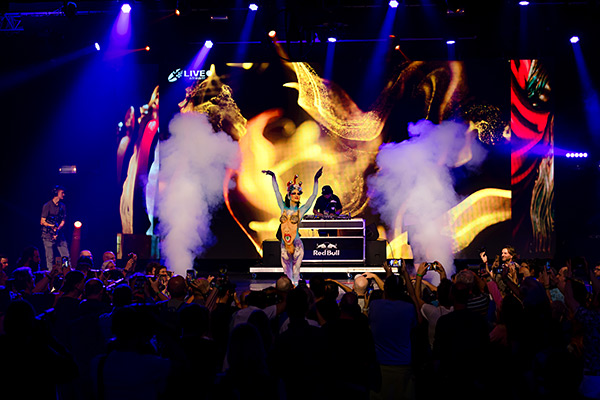 Bühne des World Bodypainting Festival 2023 mit einer Bodypainting-Performance vor einem DJ und großem LED-Screen, umgeben von Rauch und jubelndem Publikum.