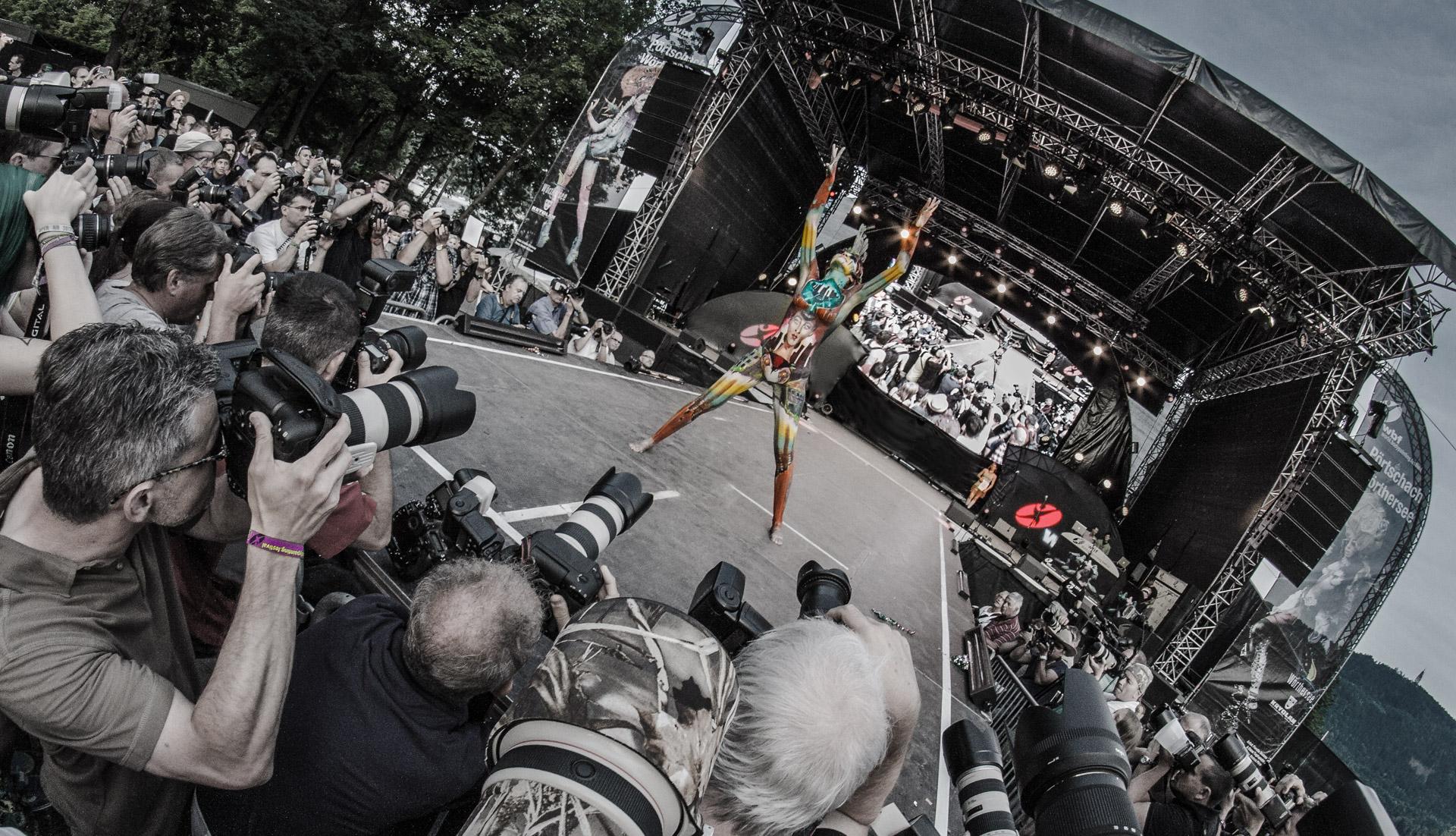 Künstlerisches Bodypainting trifft auf Performancekunst in einem farbenfrohen Wasserspektakel mit bemalten Pferden.